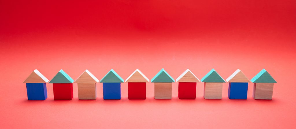 Small wooden blocks house models with roofs on red background