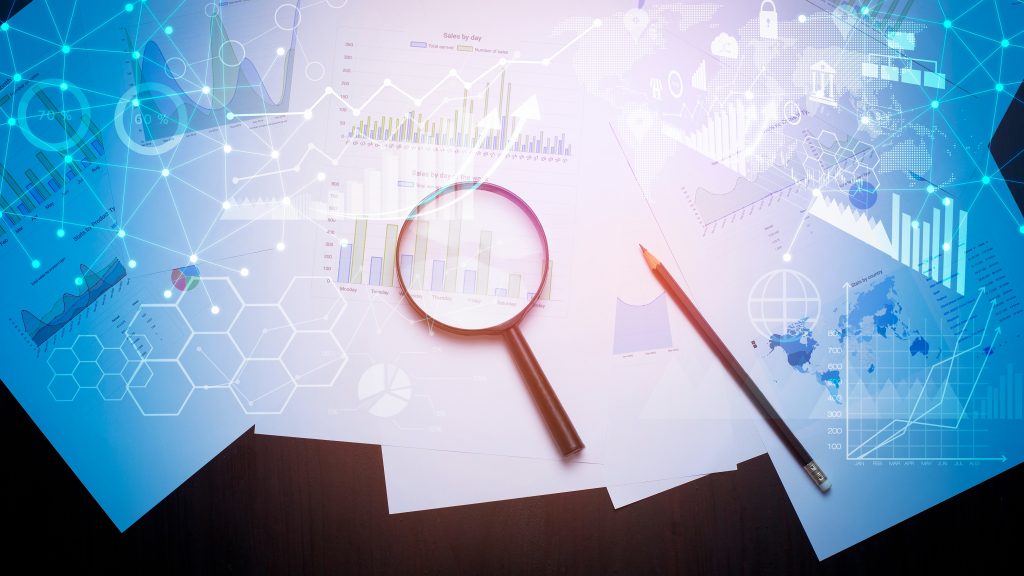 Magnifying glass and documents with analytics data lying on table