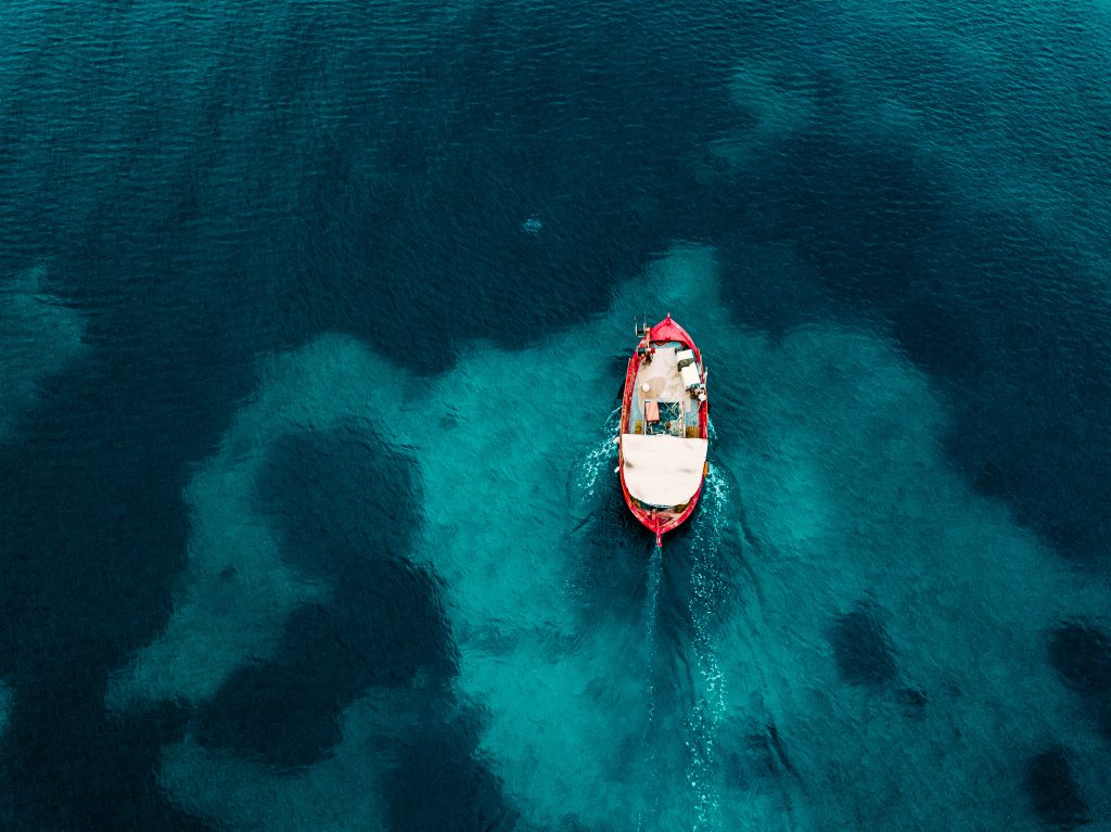 Aerial view of old fishing boat in blue sea in Greece.