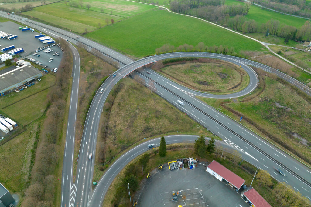 Aerial view of highway road intersection with fast moving heavy traffic. Intercity transportation with many cars and trucks
