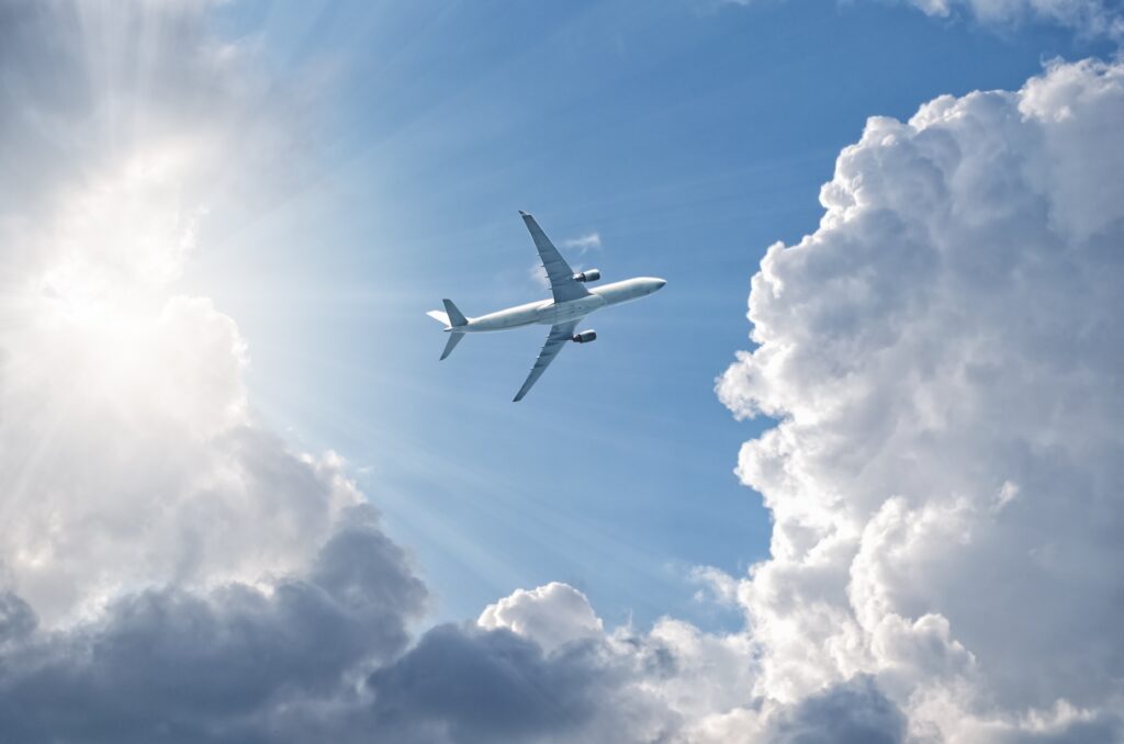 Airplane flying in blue sky,  gaining height, sun shine through