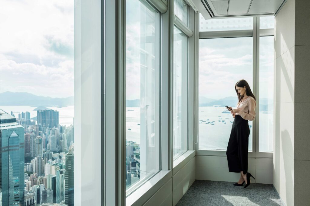 business-woman-in-skyscraper-office-window-using-s-2022-03-04-01-50-56-utc