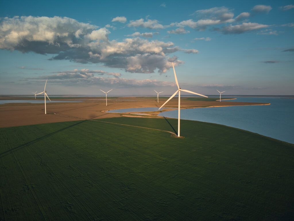 Aerial view of wind turbines and agriculture field near the sea at sunset